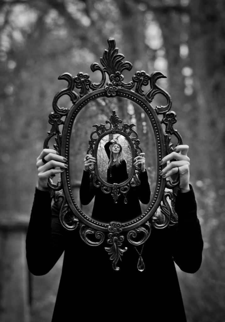 a woman holding up a mirror to her face