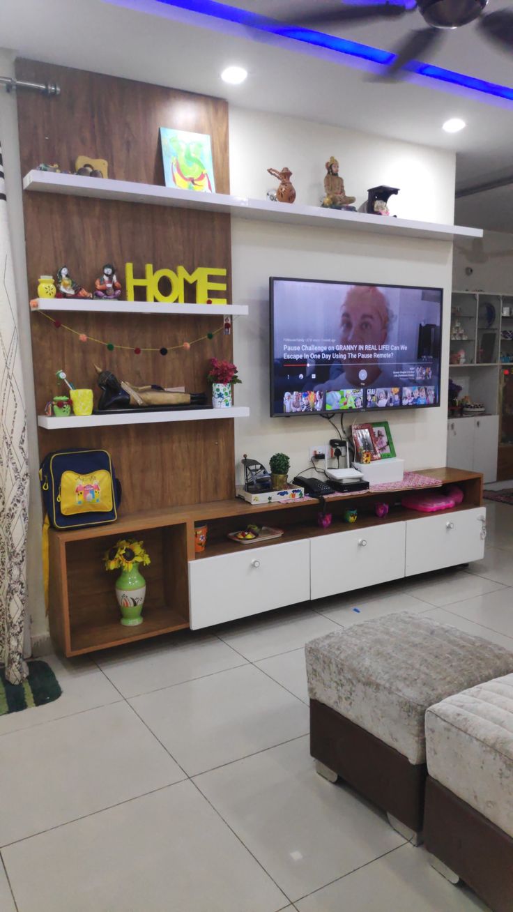 a living room with a large flat screen tv on the wall and shelves above it