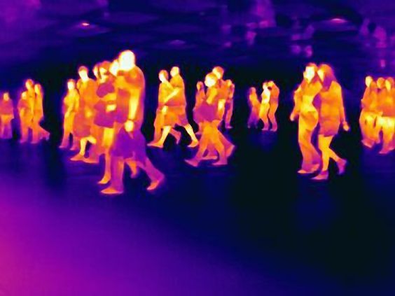 a group of people walking down a street next to each other in front of purple lights