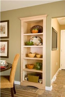 a wooden bookcase in the corner of a room next to a table and chairs