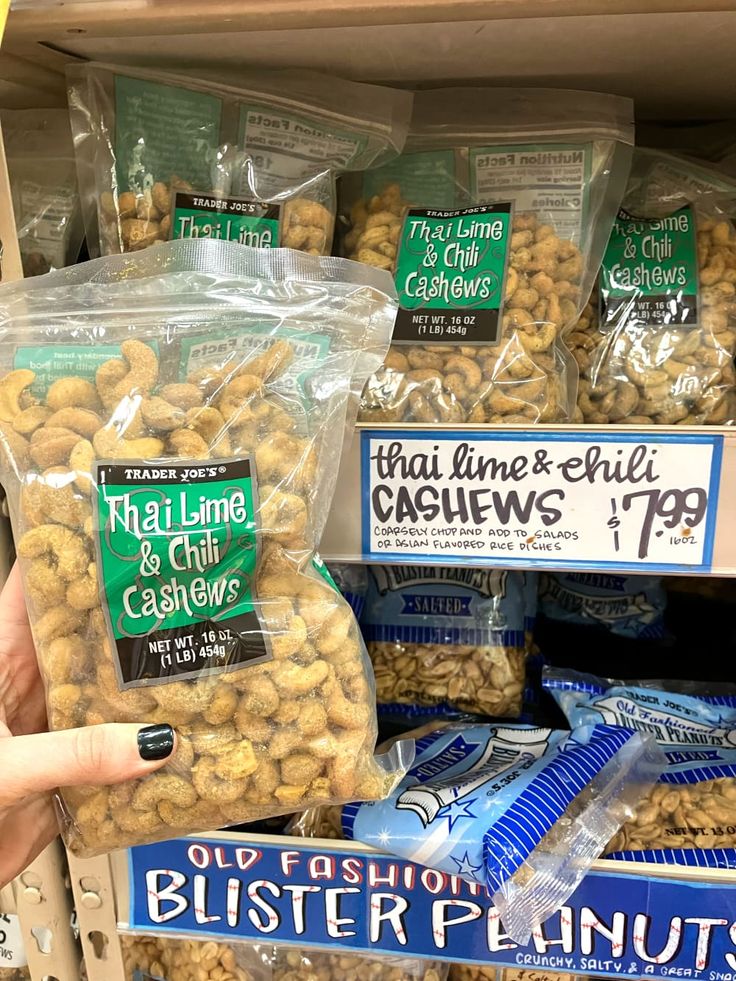 a person is pointing at some nuts on display in a grocery store's produce section