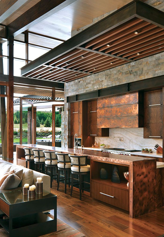 an open kitchen and living room area with wood flooring, stone walls and ceiling beams