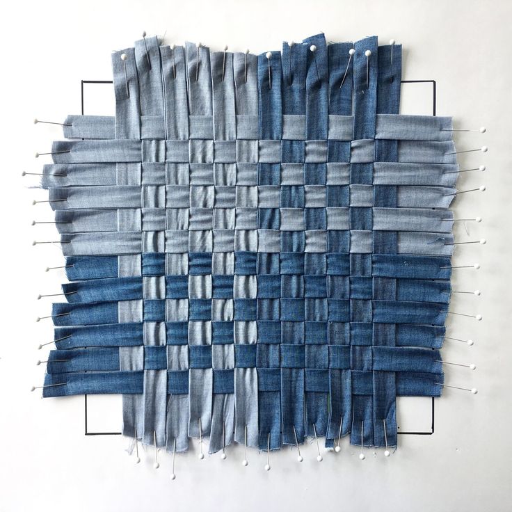 an art piece made out of jeans on a white surface with pins in the middle