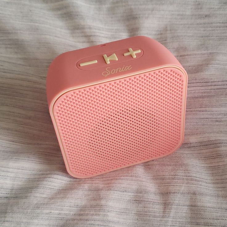 a pink portable radio sitting on top of a bed