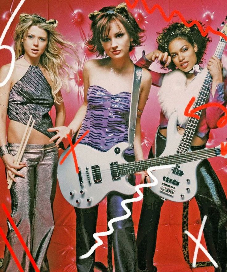 three women in costumes holding guitars and posing for the camera