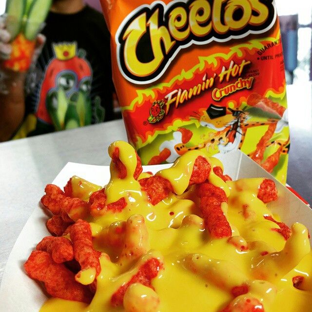 the cheetos are being served in a paper container with yellow sauce on it