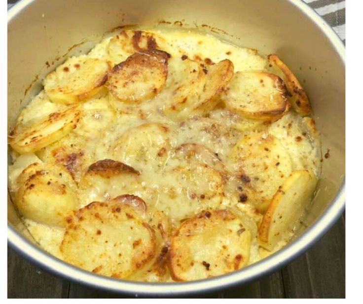 a pot filled with potatoes sitting on top of a wooden table next to an oven