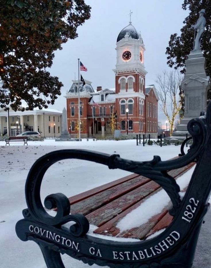 a bench in front of a large building with a clock tower on it's side