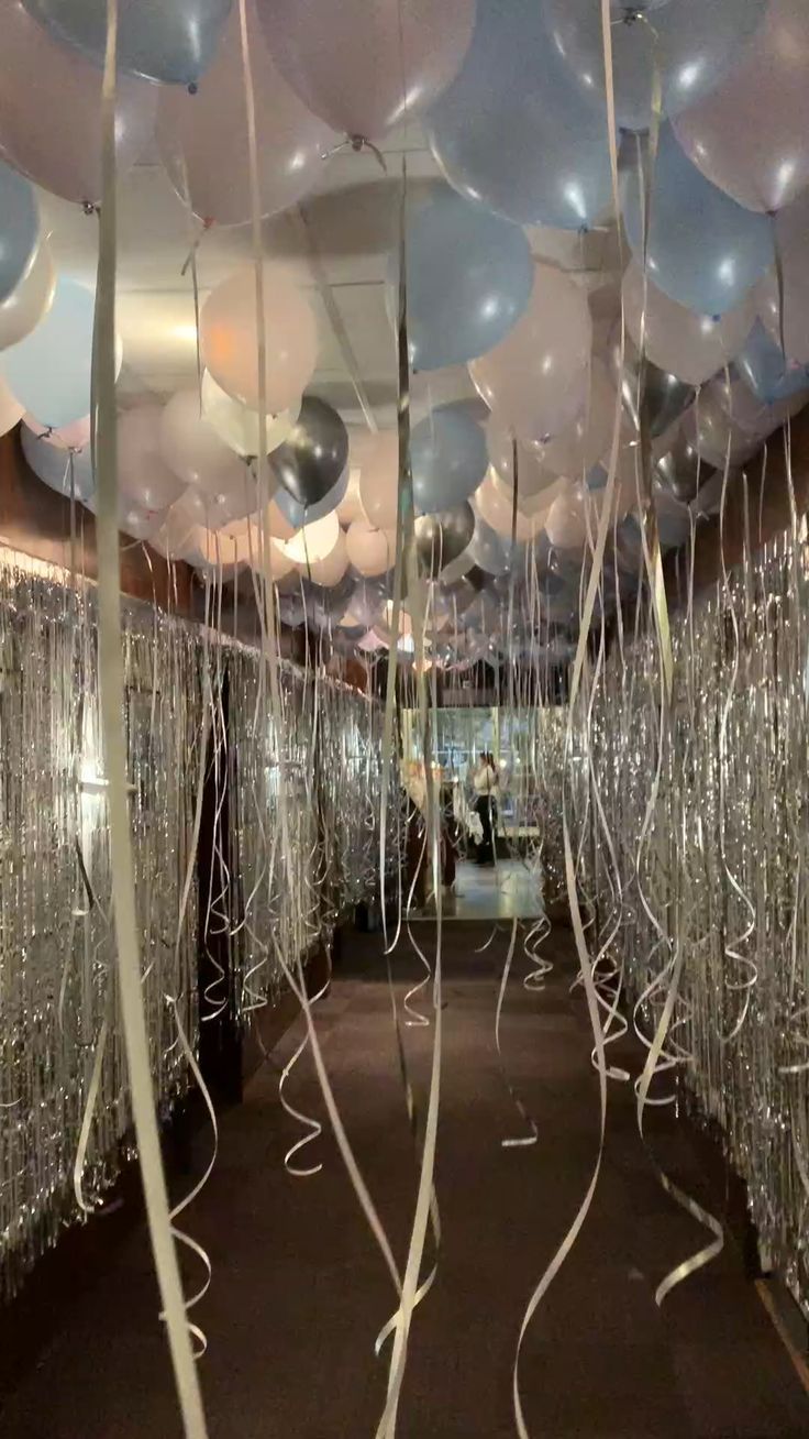 balloons and streamers are hanging from the ceiling in this hallway decorated for a party