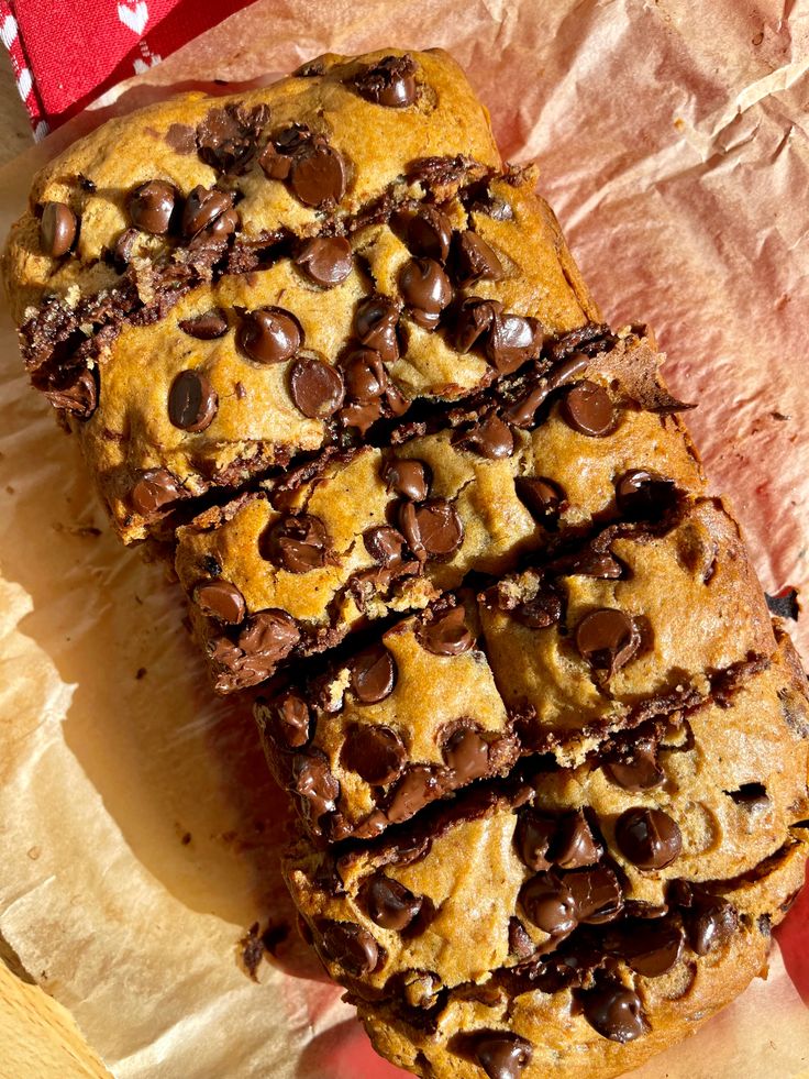 chocolate chip cookies are stacked on top of each other in front of a piece of parchment paper