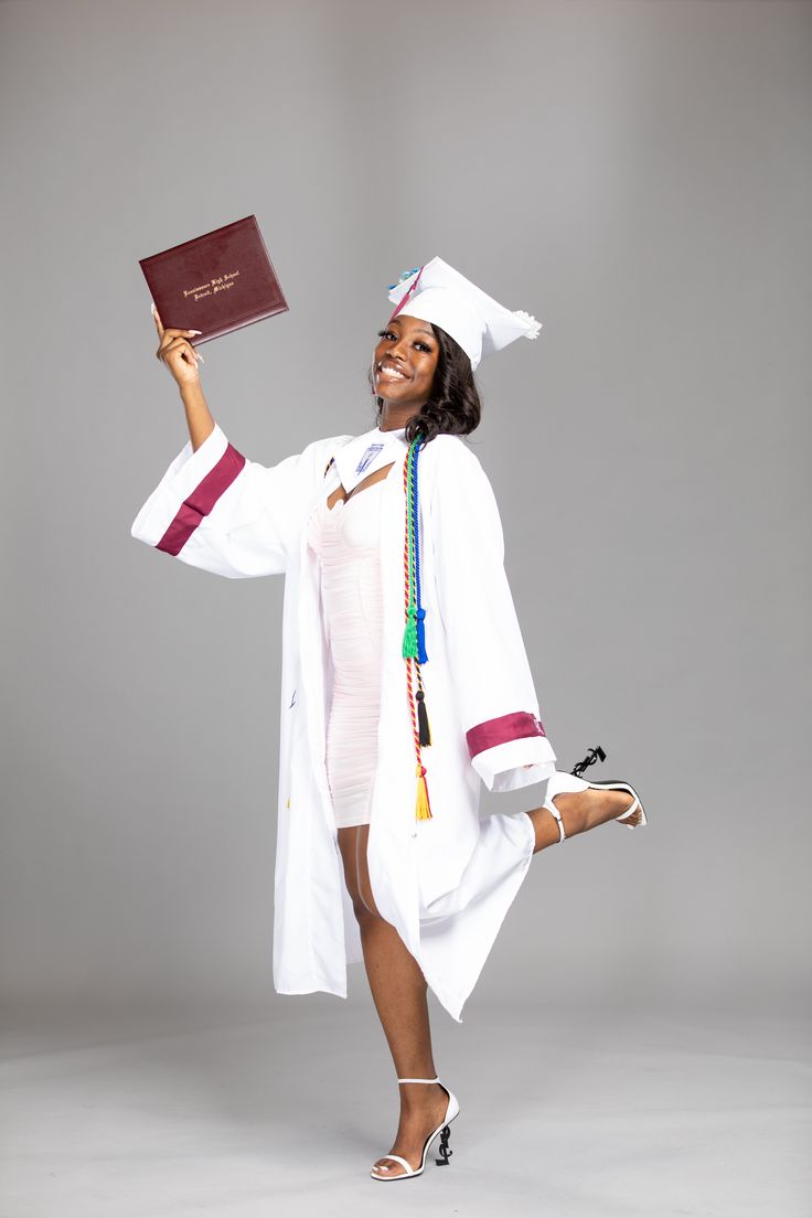 a woman in a graduation gown holding up a book