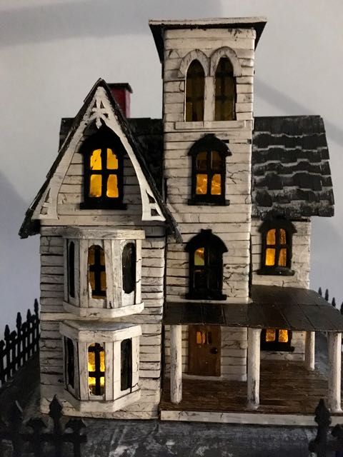 a doll house is lit up at night with the lights turned on and windows open