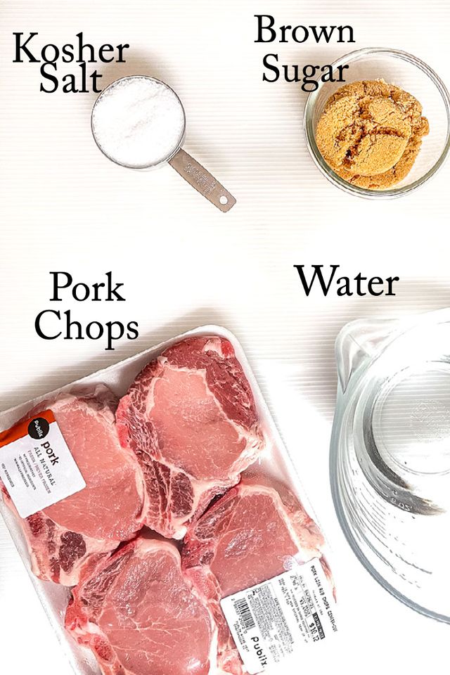 raw pork chops and other ingredients on a white table with measuring spoons, salt, pepper shaker, and sugar jar