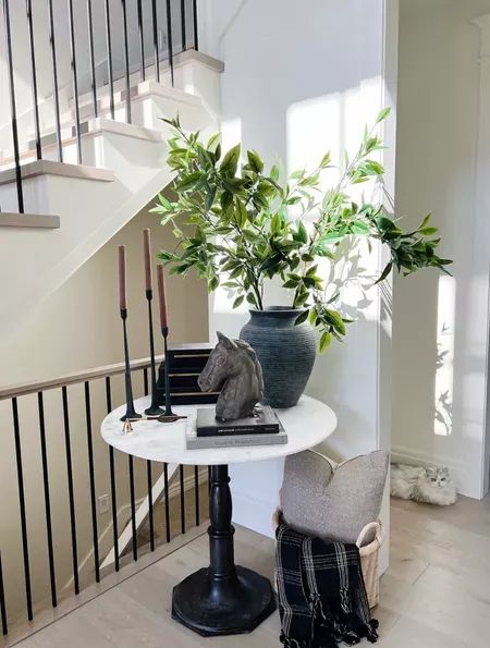 a white table topped with a plant next to a stair case