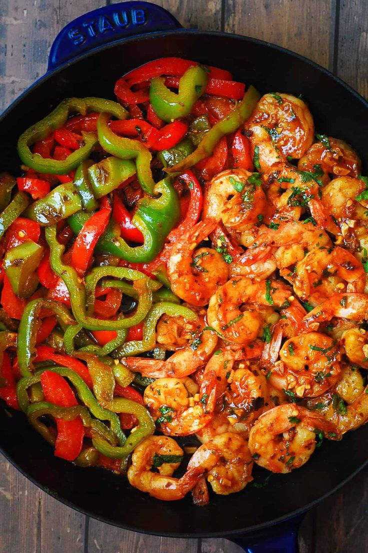 shrimp and peppers in a skillet on a wooden table