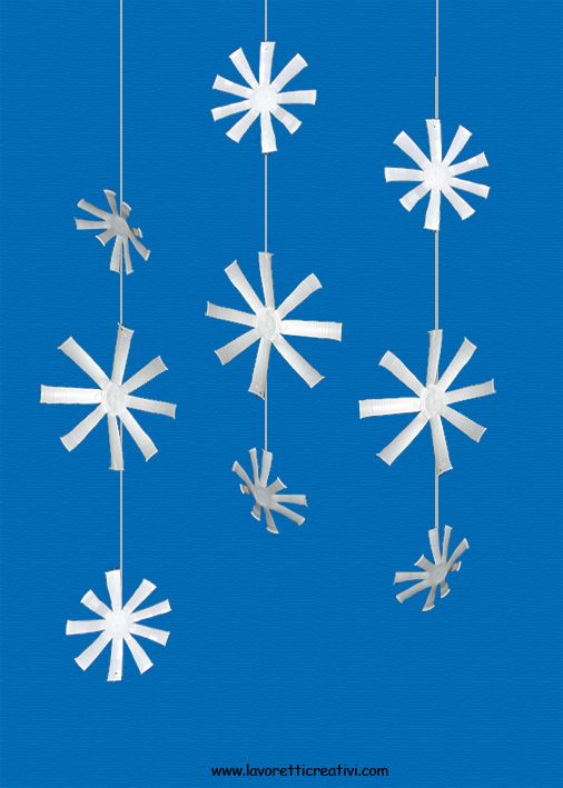 paper snowflakes hanging from strings against a blue background