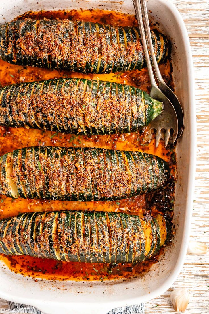 baked zucchini in a white casserole dish with a fork on the side