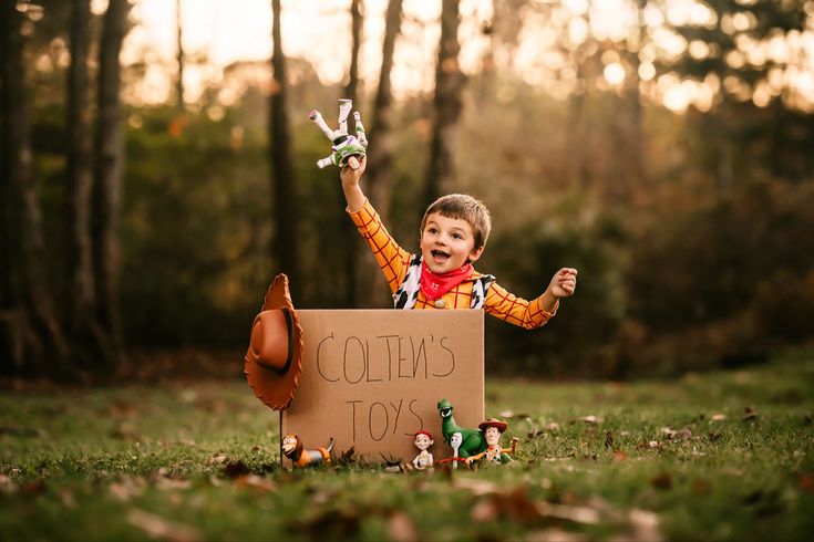 a little boy sitting in the grass holding a sign