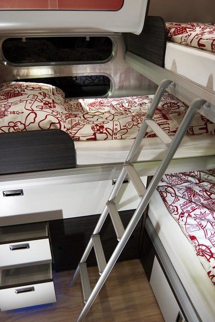 bunk beds with red and white comforters in a small room on a ship or boat