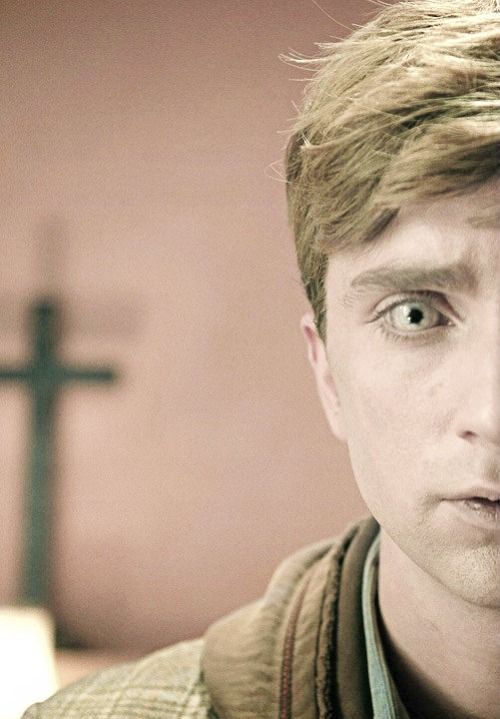 a close up of a person with a cross in the background