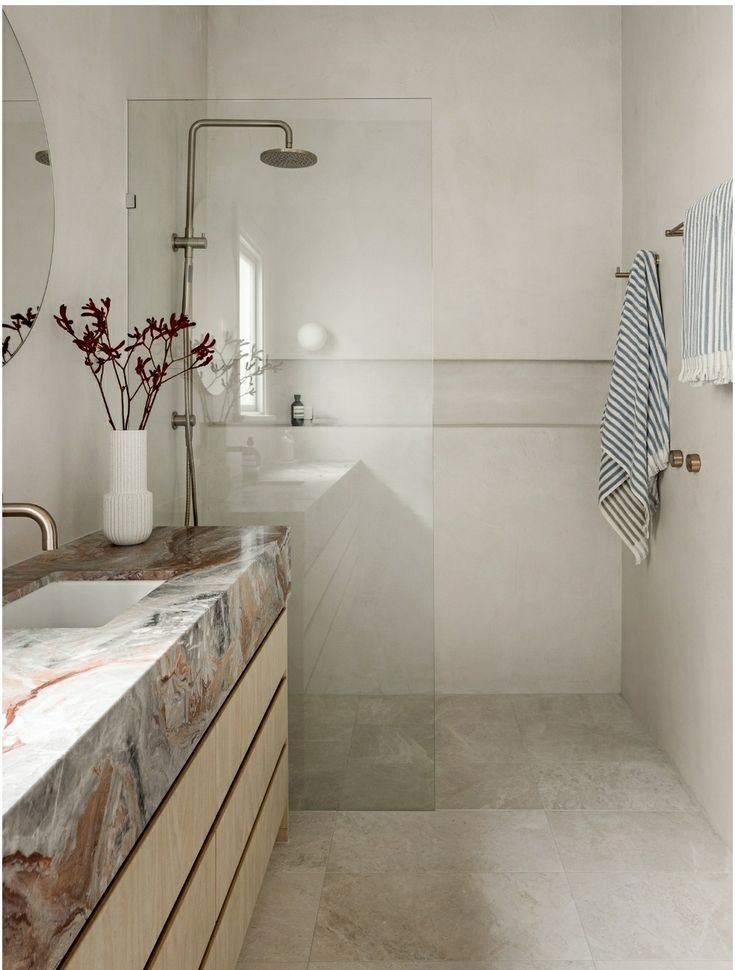 a bathroom with marble counter tops and white walls, along with a large mirror on the wall