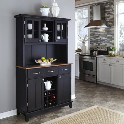 a kitchen area with a black cabinet and white vases