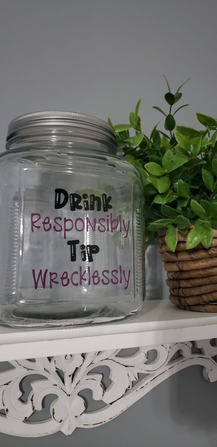 a glass jar sitting on top of a white shelf next to a potted plant