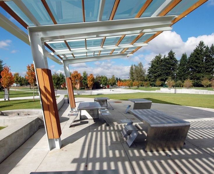 an empty picnic area with benches and pergolated roof