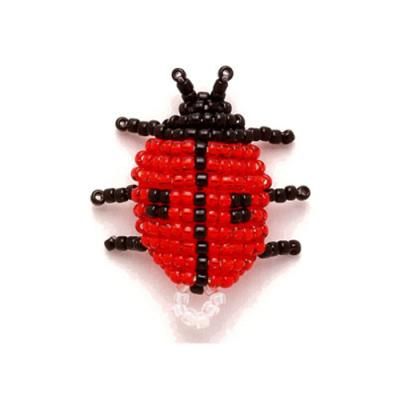 a red and black beaded ladybug brooch sitting on top of a white surface