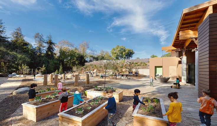 several children are standing in front of raised garden beds