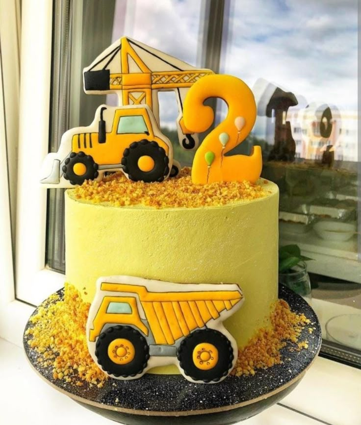 there is a yellow cake with a construction truck on it and the number 3 in front