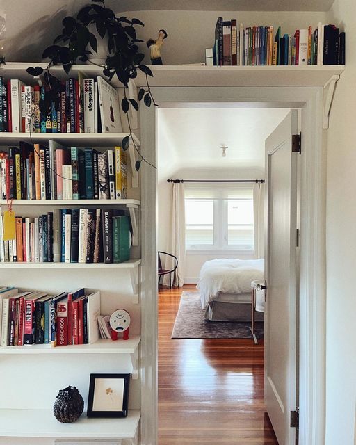 a book shelf filled with lots of books next to a doorway leading into a bedroom