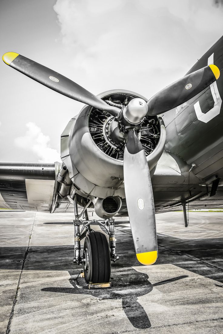 an old propeller plane sitting on top of an airport tarmac with the propellers still attached