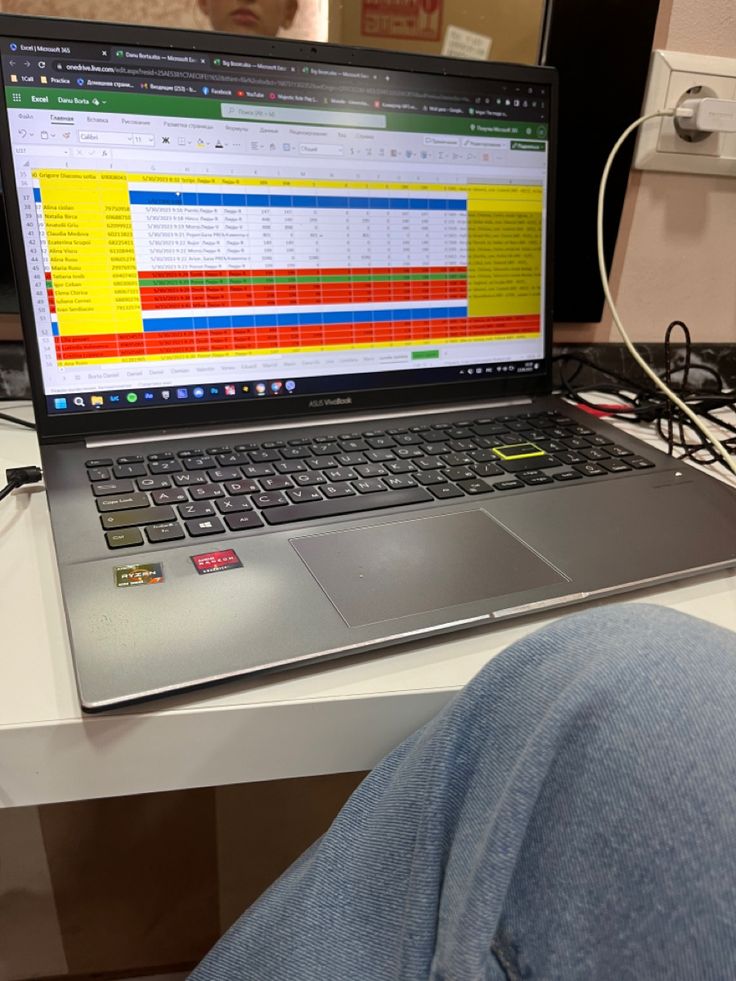 an open laptop computer sitting on top of a white desk next to a person's legs