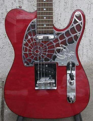 a red guitar sitting on top of a metal stand