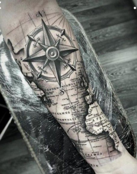 a man's arm with a compass tattoo on the forearm and an island in the middle