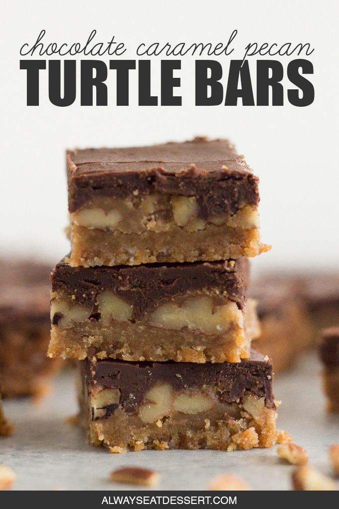 three pieces of chocolate peanut butter bars stacked on top of each other with nuts scattered around them