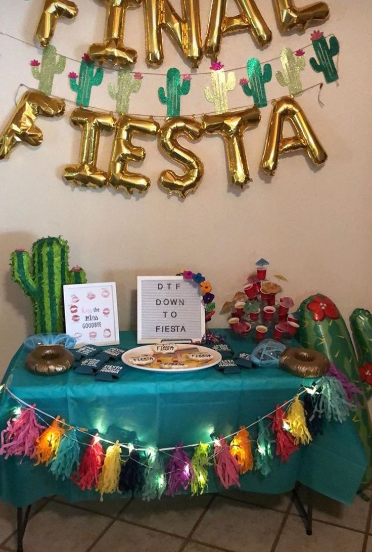 a table that has some food on it and balloons hanging from the wall behind it