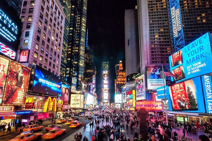 a busy city street filled with lots of neon signs and tall buildings in the night