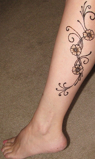 a woman's foot with a flower tattoo on the side of her left leg