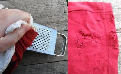 a person holding a grater over a piece of red cloth on top of a wooden table