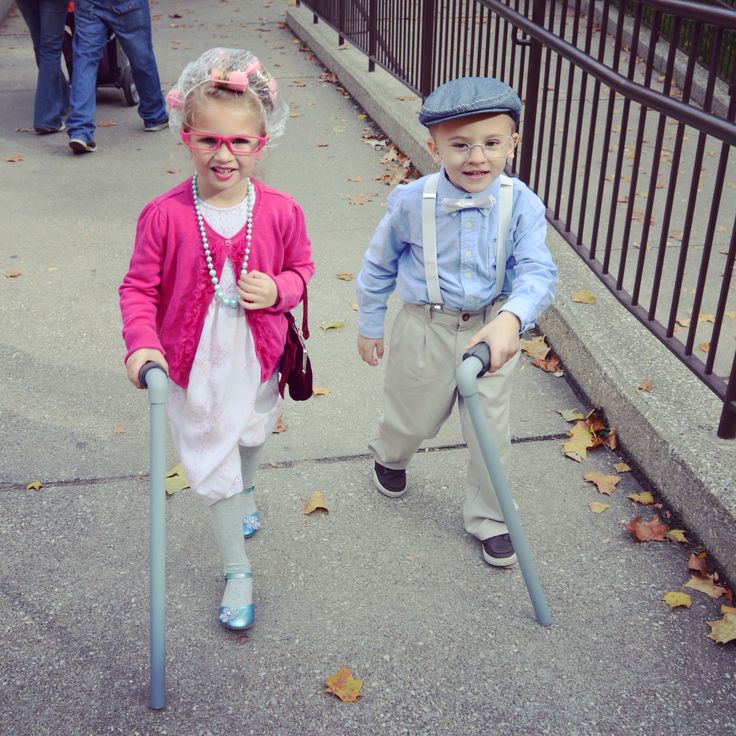 two young children walking down the sidewalk with crutches