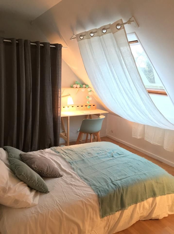 a bed sitting under a window next to a desk with a computer on top of it