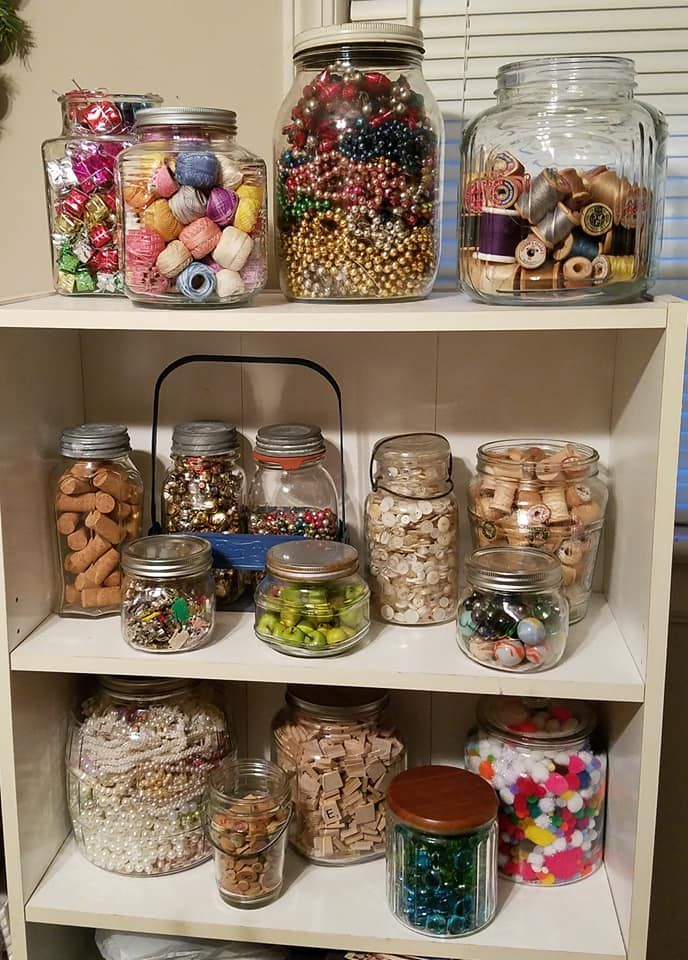 a shelf filled with lots of different types of beads and other things in jars on top of it