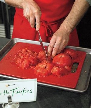 a man in an apron cutting tomatoes on a tray