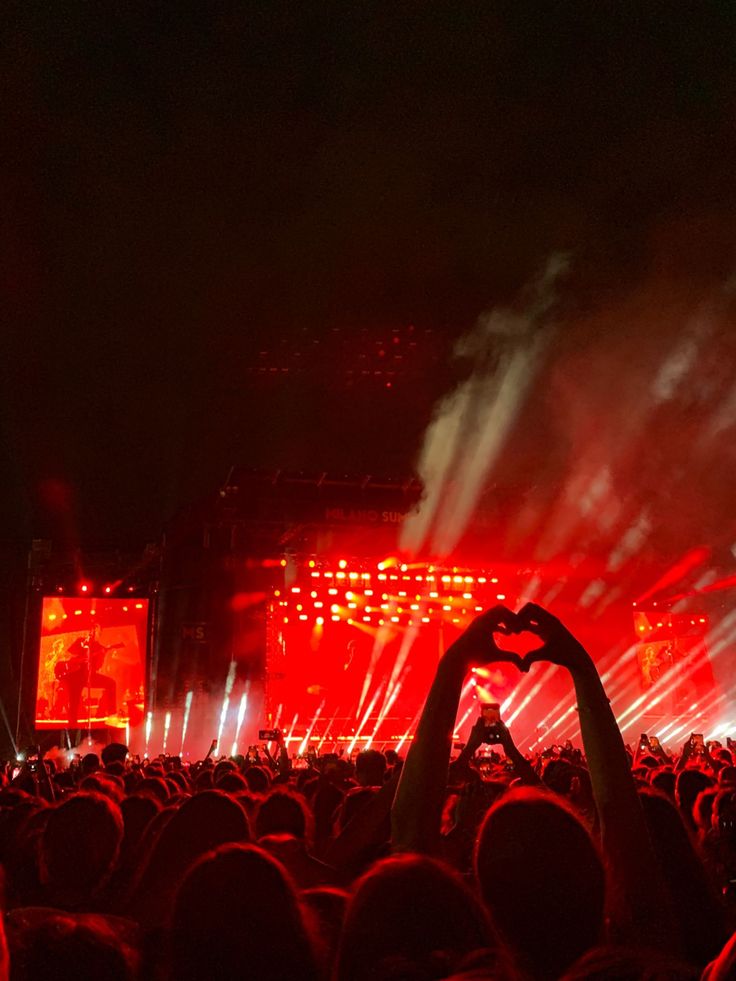 a large group of people at a concert with their hands up in front of the crowd