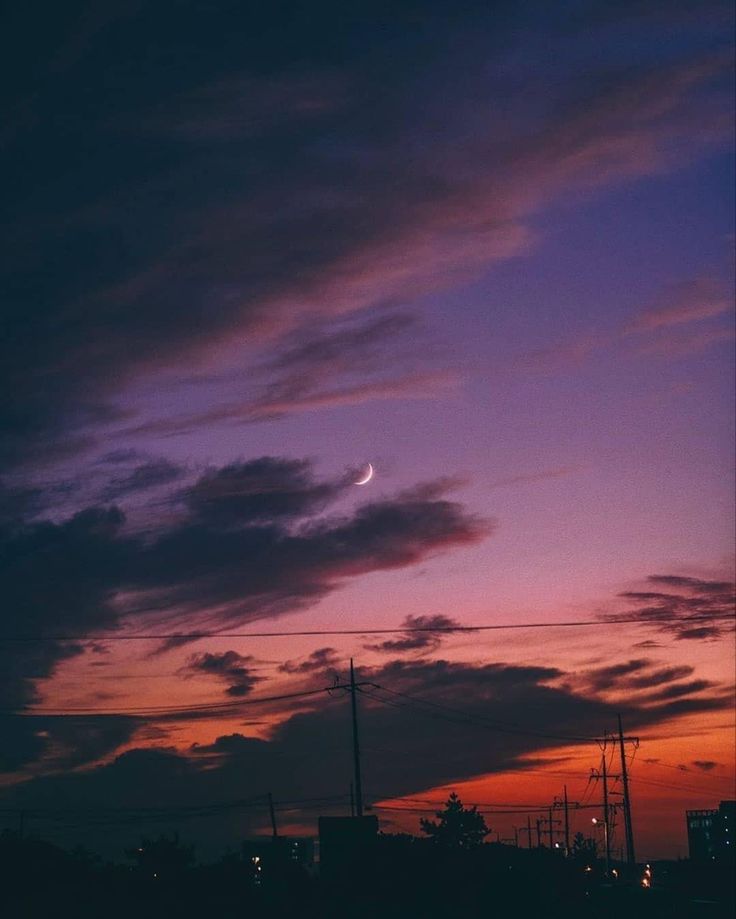 the sun is setting behind some clouds in the sky with power lines and telephone poles