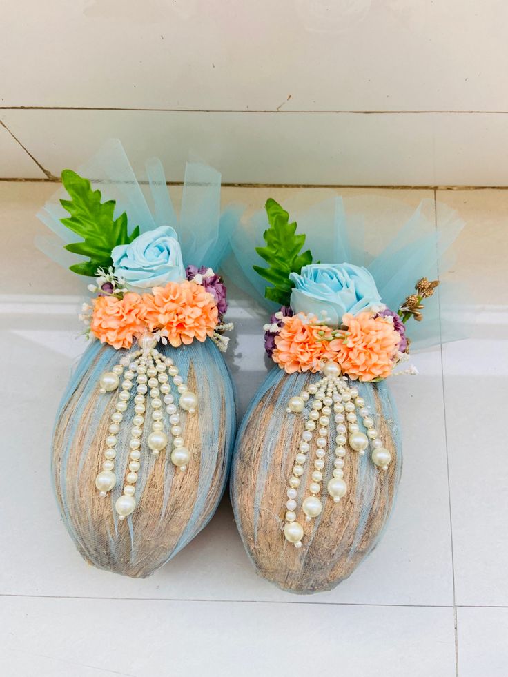 two vases with flowers and pearls on them sitting on the floor next to each other