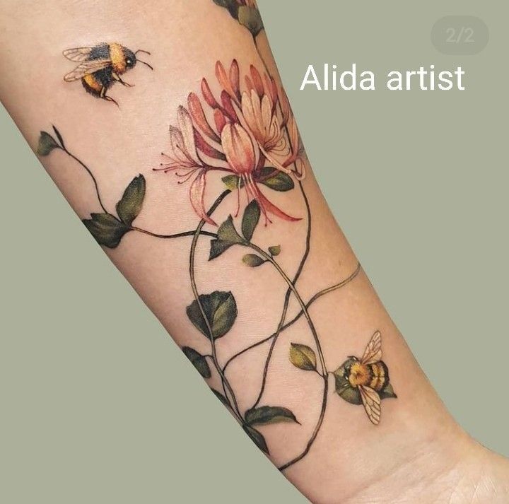 a woman's arm with flowers and a bee on the back of her arm