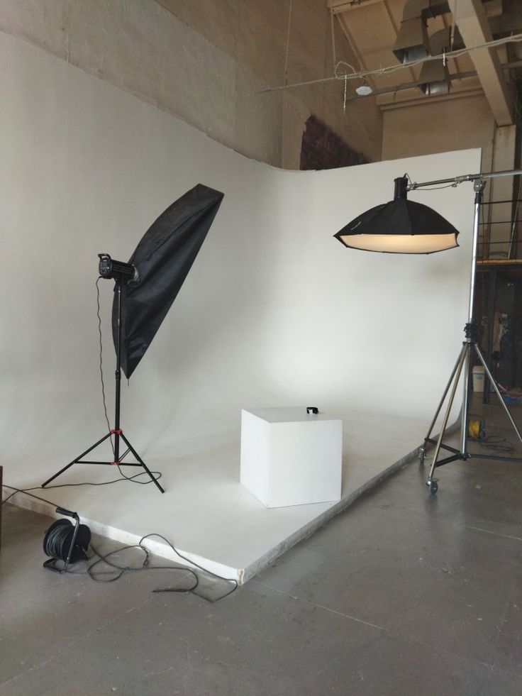 an empty photo studio with two lights and one light on the floor in front of it